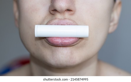 close up of bottom of the face of a woman using natural ingredients lip balm, white blank pack. Putting Lip Protector Lipstick on, hygienic balm from wax with honey add. lips home care.