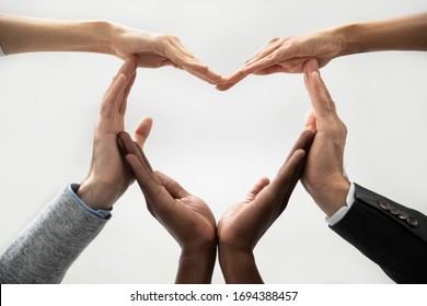 Close up bottom view concept of diverse business people join hands forming heart. Show unity and support, protection of business. Multiracial colleagues involved in team building activity for charity.