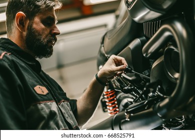 Close up bottom view of the handsome motorcycle mechanic checks the oil level in the motorcycle. The sports bike is on the lift. - Powered by Shutterstock