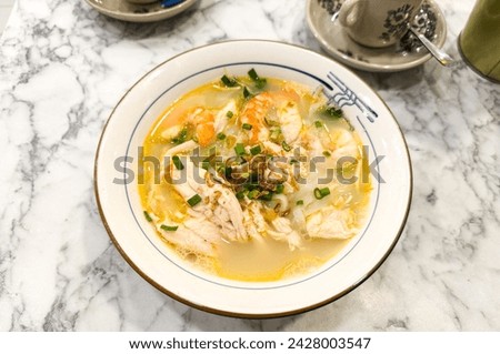 Close up of a bowl of Ipoh hor fun or shredded Chicken and prawn Chinese rice noodle soup, Singapore and Malaysian foods.