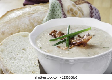 Close Up Of A Bowl Of Seafood Soup With Bacon And Chives Garnish And Rustic Loaf Of Bread