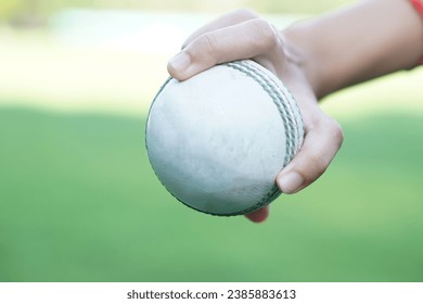 Close up bowler hand holds a white leather cricket ball. Concept, sport equipment. Competitive sport. A cricket ball is made with a core of cork, covered by a leather case. Ready to bowl to  batsman - Powered by Shutterstock