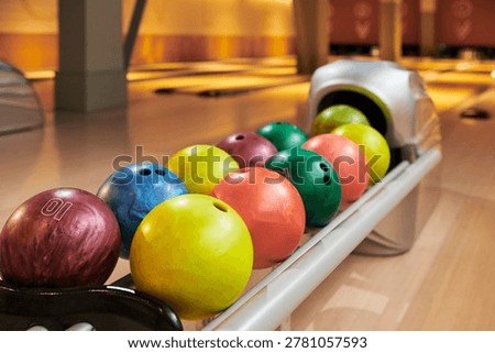 Close up of bowling balls resting in return rack on lane, representing leisure entertainment and group recreation. Suitable for sports venue marketing, event promotion, copy space