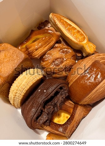 Close up box of assorted bakery and pastries- chocolate croissant, Pain Suisse, Danish pie and Brioche