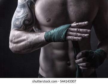 Close up of a boxer putting on straps preparing for combat on a dark background