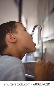 Close Up Of Boy Drinking Water From Faucet At School