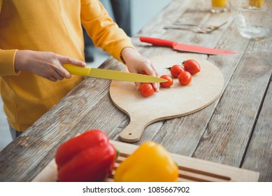 Close Up Of Boy Hands Slicing Vegetables For Salad On Cooking Board