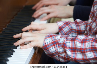 Close Up Of Boy Playing Piano Duet With Teacher