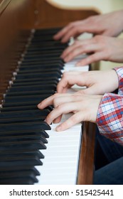 Close Up Of Boy Playing Piano Duet With Teacher