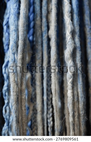 Close up of braid extensions in blue and grey cool tones forming textured background. Concept hair design, beauty materials, winter palette, fashion pattern, cold color style.