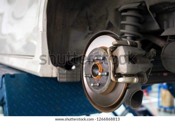 Close up of Brake Disc of\
the vehicle for repair.Automobile mechanic in process of new tire\
replacement.Car brake repairing in garage.Car Service and\
technician concept.