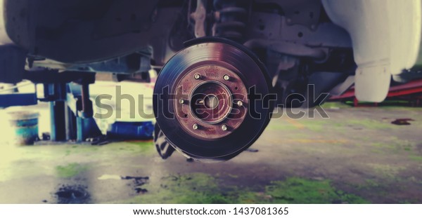 Close up of Brake Disc of the vehicle for\
repair,Automobile mechanic in process of new tire replacement,Car\
brake repairing in\
garage.