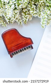 Close up of Branch of blossoming bird cherry and  Miniature copy of the piano on light gray background	with music paper