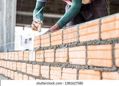 Close Up Of Bricklayer Worker's Hand Installing Red Brick With Trowel Putty Knife For New House Building At Construction Site.