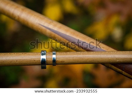 Close up of bride and groom's wedding rings on pool cues with rustic background