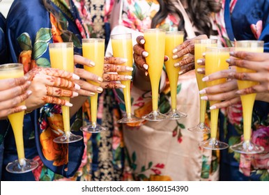 Close Up Of Bride Maids With Henna Holding Glass Of Orange Champaign Mimosa Cocktail In A Toast