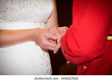 Close Up Of Bride In White Lace Gown And Groom In Red Rcmp Uniform Holding Hands And Exchanging Rings During The Wedding Ceremony