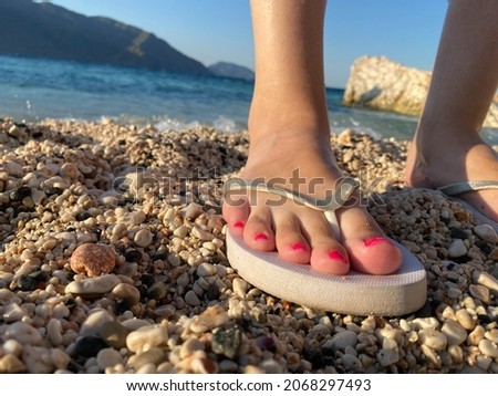 A close up of brides legs in flip flops on a beach with manicured nails.