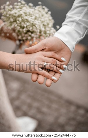 Close up of a bride's palm with a wedding ring in her groom's hand