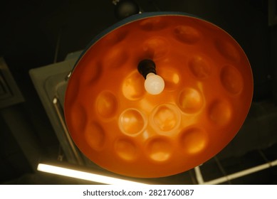 Close up of a bright light bulb inside a textured orange lamp shade.