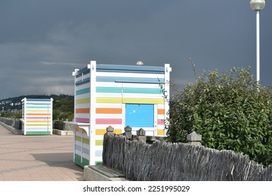 close up of Brightly coloured  wooden buildings.  The rainbow striped little sheds line a promenade at a coastal resort ready for use as little retail shops - Powered by Shutterstock