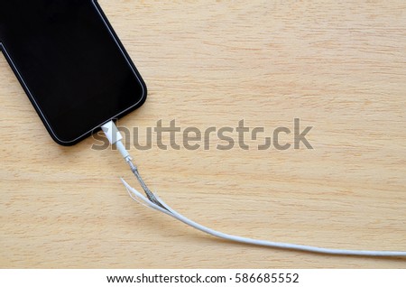 Close Up the Broken Smart Phone Charger Cable on wooden Background. 
