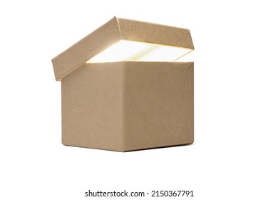 Close Up Of Brown Cardboard Gift Box With Slightly Opened Lid And Bright Light Inside The Container On White Background As A Concept For A Treasure And Valuable Souvenirs