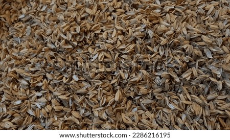 Close up of a brown color 'Rice hulls' heap against a bright nature background.