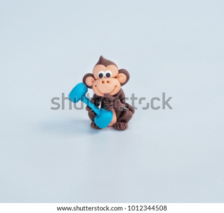 Close up of brown monkey clay plasticine is lifting dumbbell with naughty face on white background concept healthy , exercise , diet