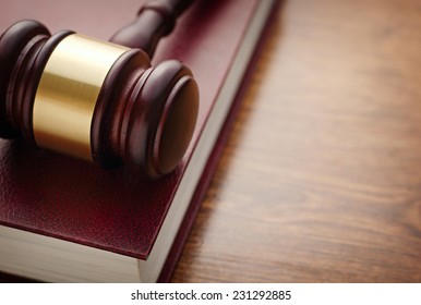 Close up Brown Wooden Gavel and Maroon Book on Top of Wooden Table, Emphasizing Legal or Law Concept