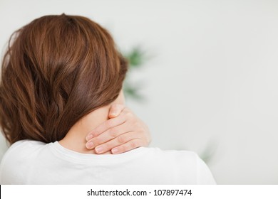 Close up of a brunette woman massing her neck in a room