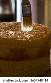 Close Up Of A Brush Cleaning Up Crumbs From A Fresh Baked Vanilla Cake.