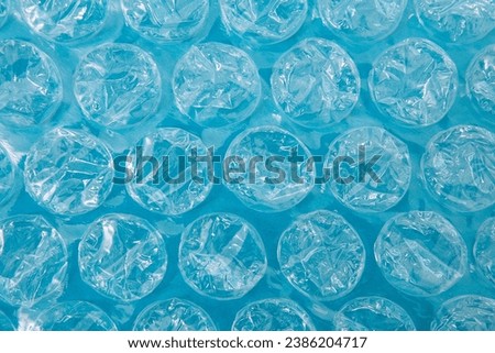 Close up bubble wrap on the blue background, air bubble packaging texture. Polyethylene packaging for fragile items, postal delivery service. Non-eco-friendly packaging for glass or breakable items