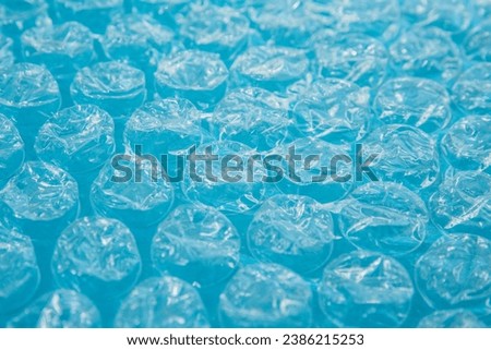 Close up bubble wrap on the blue background, air bubble packaging texture. Polyethylene packaging for fragile items, postal delivery service. Non-eco-friendly packaging for glass or breakable items