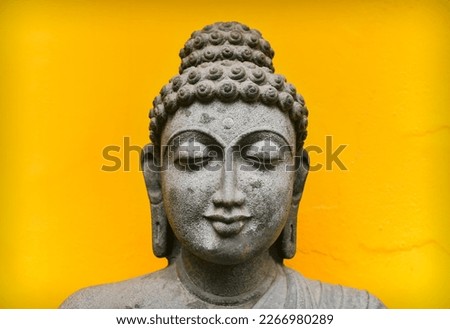 Close up Buddha Face Statue Isolated On Yellow French Colony Wall Background, Granite Buddha Statue Portrait.