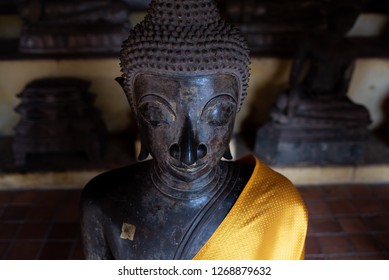 A Close Up Of A Buddhist Statue With A Gold Sash At A Temple 