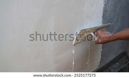 close up A builder's hand using trowel and plaster for plastering and skim coating wall. A plasterer is doing plasterwork. Copy space.