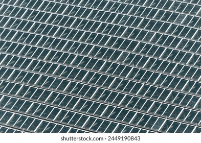 A close up of a building with many windows. The windows are all the same size and are arranged in a grid pattern. The building appears to be a modern structure with a lot of glass