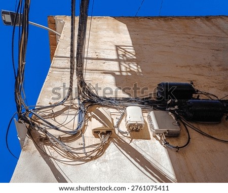 Close up of building wall with multiple tangled electrical and internet cables, urban infrastructure, telecommunications and disorder concept. Horizontal photo