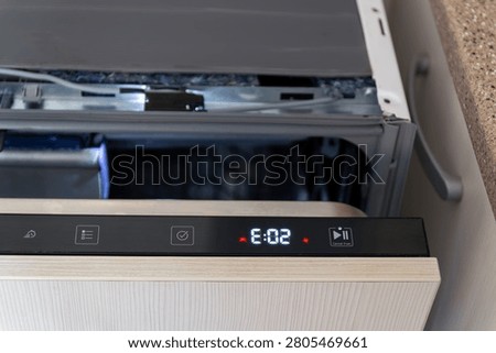 Close up of built-in dishwasher panel displaying technical error or failure during cycle. Broken modern dishwasher machine