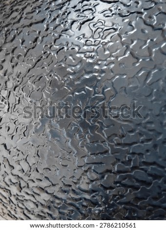 Close up of a bumpy and wrinkled black textured surface with glossy finish. Abstract dark industrial background or metallic pattern backdrop.