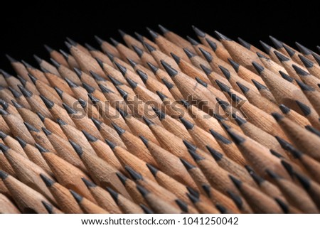 Close Up of bunch of identical sharp graphite pencils on black background. Studio shot. Concept of uniformity. Concept of similarity.
