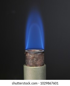 Close up of a Bunsen burner muzzle with low-tipped blue flame used of flammability tests according to UL standard.