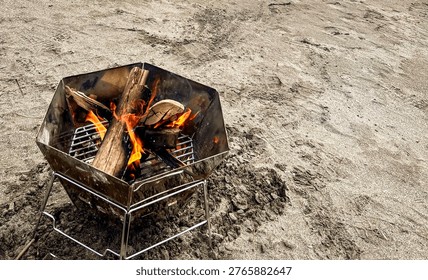 Close up of burning campfire in hexagonal fire pit on sandy beach