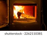 Close up of burning wooden logs blazing in fire flames inside wood burning stove with open glass door in cosy warm home living room.