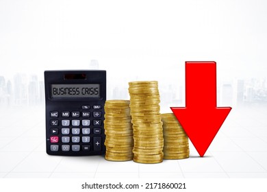 Close Up Of Business Crisis Text On The Calculator And Piles Of Gold Coins With Declining Arrow In The Studio. Isolated On White Background