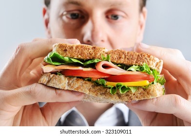 Close Up Of A Business Man Eating A Healthy Ham, Cheese, Tomato Sandwich, Selective Focus On Food 