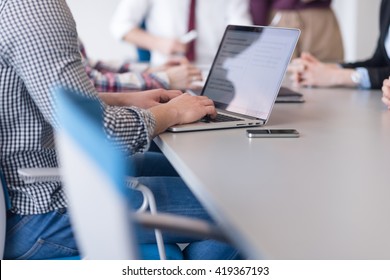 Close Up Of Business Man Hands Typing On Laptop Computer At Modern Startup Office, Blured Team In Meeting, People Group In Background