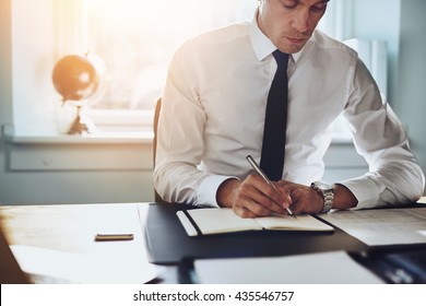 Close up of business man in shirt and tie working in his office writing in a classic note book - Powered by Shutterstock