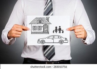 Close Up Of A Business Man,holding White Card With House,car And Family Drawing Inside.Isolated Against Grey Background.